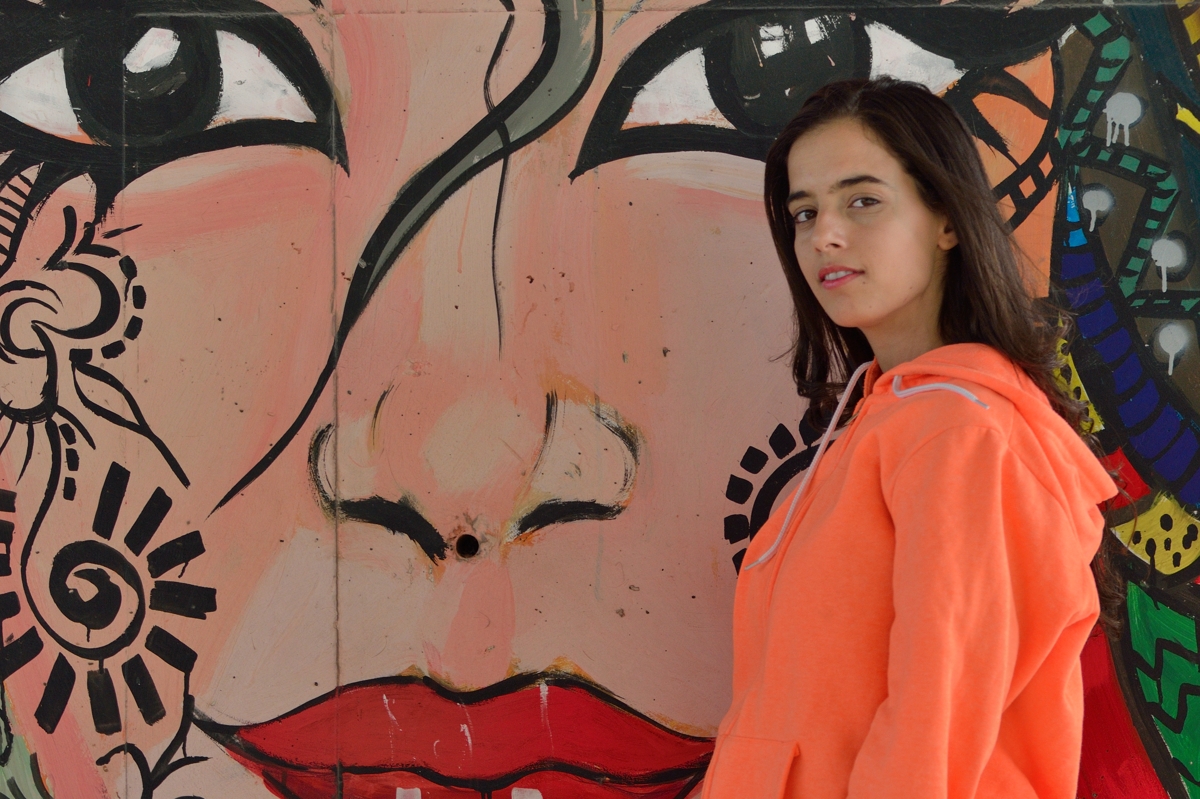 Abir devant un visage peint, street art du viaduc de Tunis 