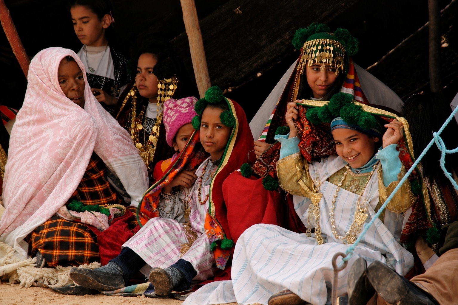 Une famille amazighe réunie sous une tente à Douz, vêtue de costumes traditionnels et de bijoux.