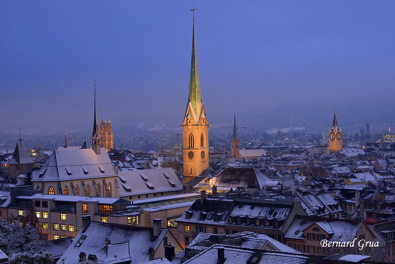 Zurich enneigée à l’heure bleue, avec la flèche du Fraumünster
