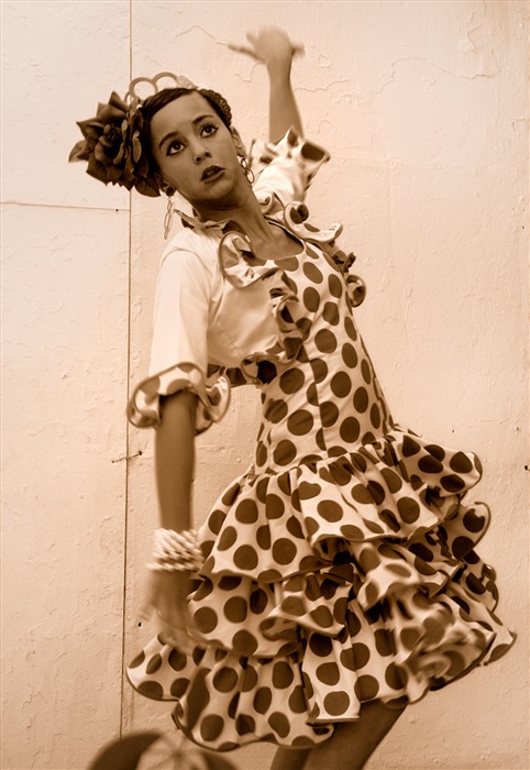 Jeune femme dansant le flamenco en robe andalouse blanche à pois, ornée de volants, pendant la feria d’Arcos de la Frontera. 