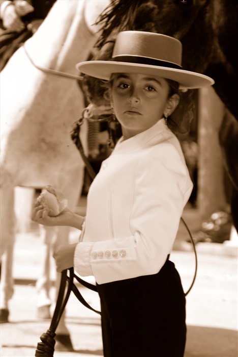 Anna en tenue équestre andalouse, portant un chapeau à larges bords et tenant les rênes de son cheval. 