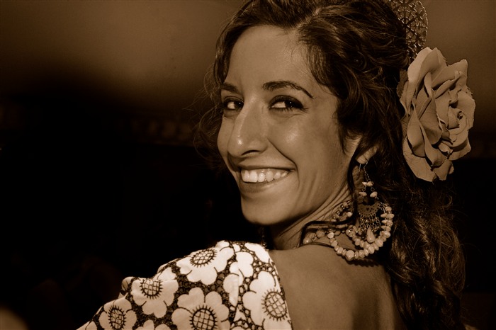 Portrait d’une jeune femme en tenue andalouse, avec une grande fleur dans les cheveux et des bijoux traditionnels.