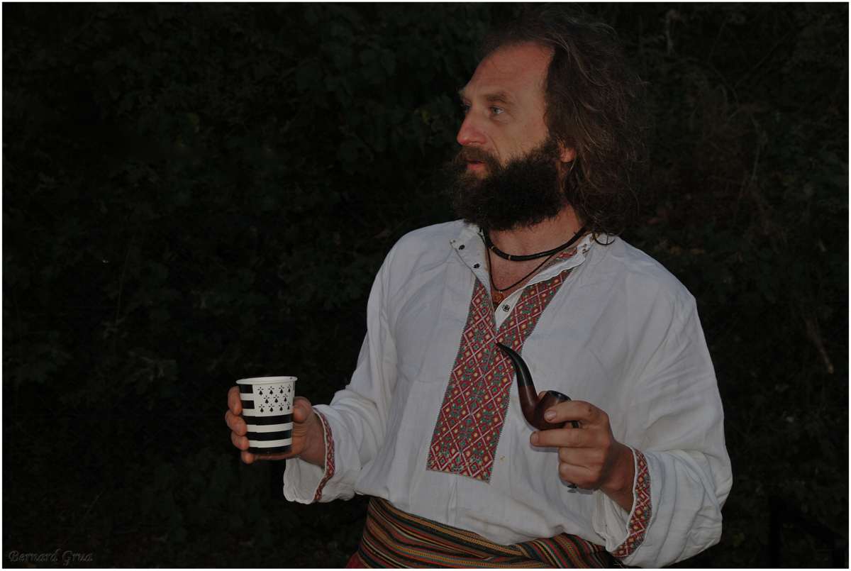 Taras Beniakh en costume traditionnel cosaque, portant une chemise blanche brodée et une ceinture rouge.