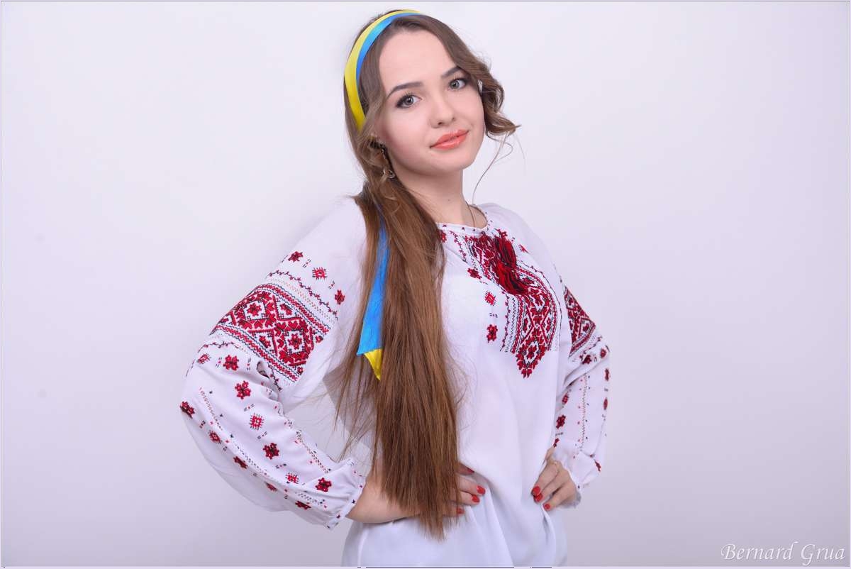 Elena portant une vychyvanka ukrainienne brodée, un ruban bleu et jaune autour de la tête et les cheveux dénoués.