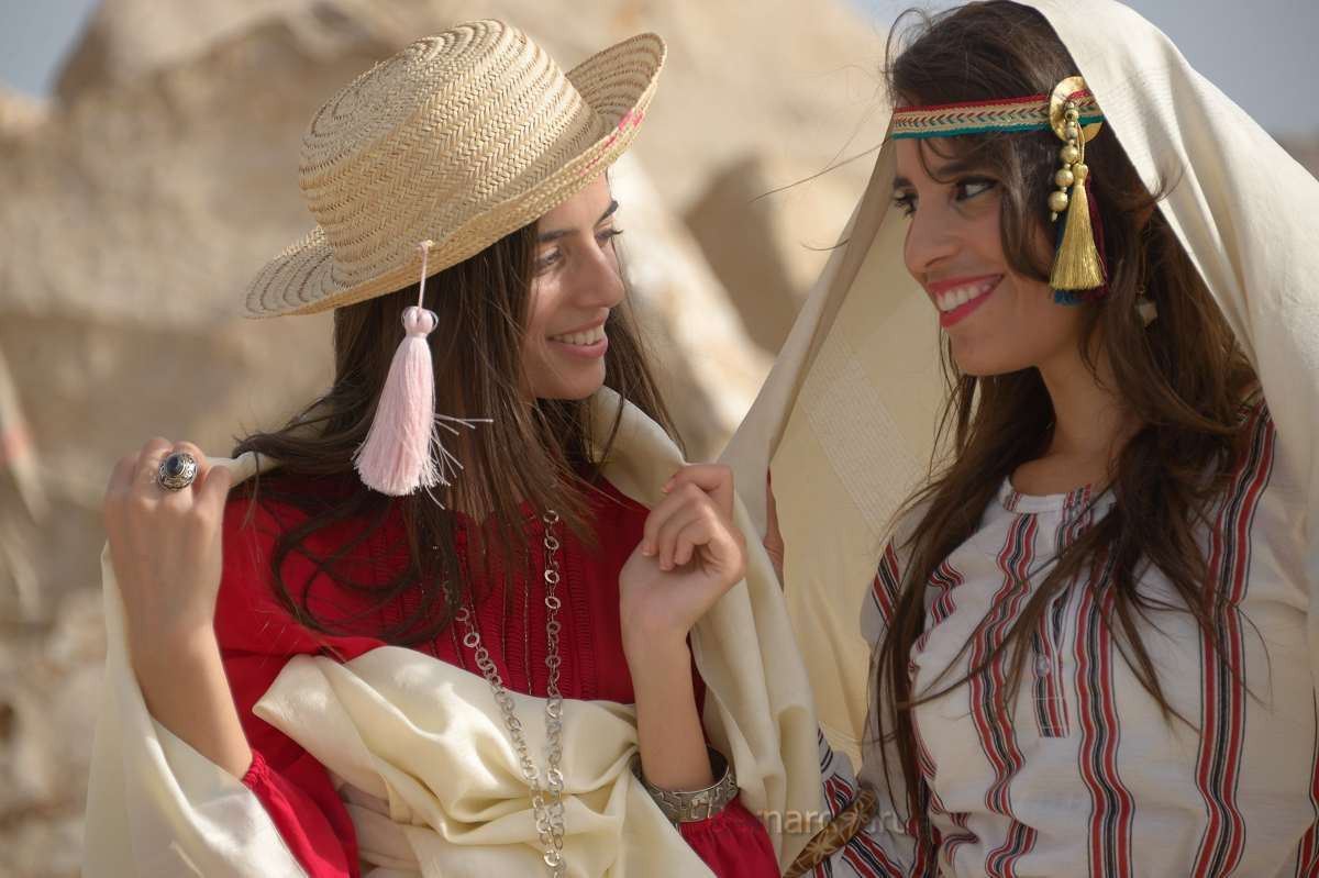 Abir et Hiba vêtues de tenues traditionnelles tunisiennes, souriant sous un voile blanc à Sidi Bou Saïd.