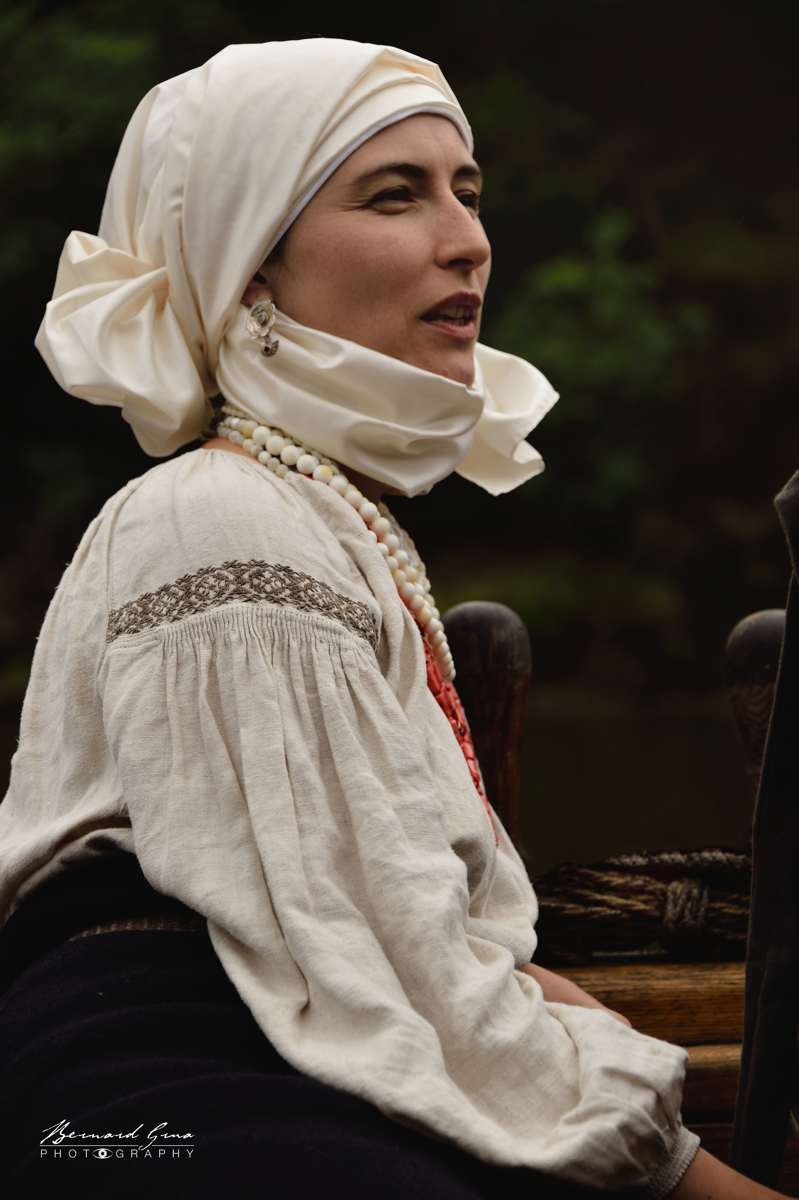 Jeune femme en costume traditionnel cosaque, portant une coiffe blanche et une chemise brodée.