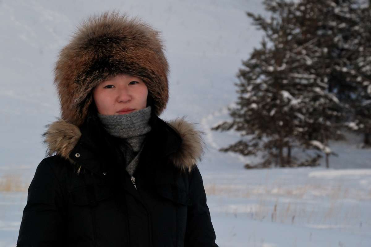 Rimma, jeune femme iakoute, sourit devant un paysage enneigé.