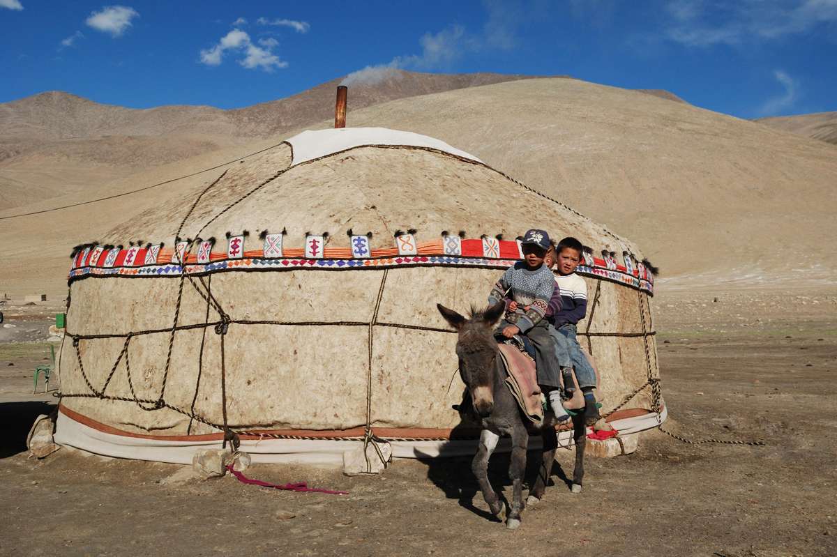 Des enfants kirghizes à dos d'âne près d'une yourte à Zarburuliuk Jailoo, dans le Pamir tadjik. Alt 4 150 m