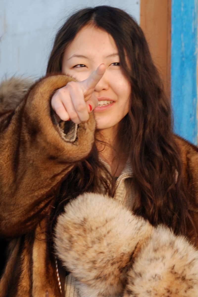 Katya, jeune femme iakoute, vêtue d'un manteau de fourrure dans un paysage enneigé.