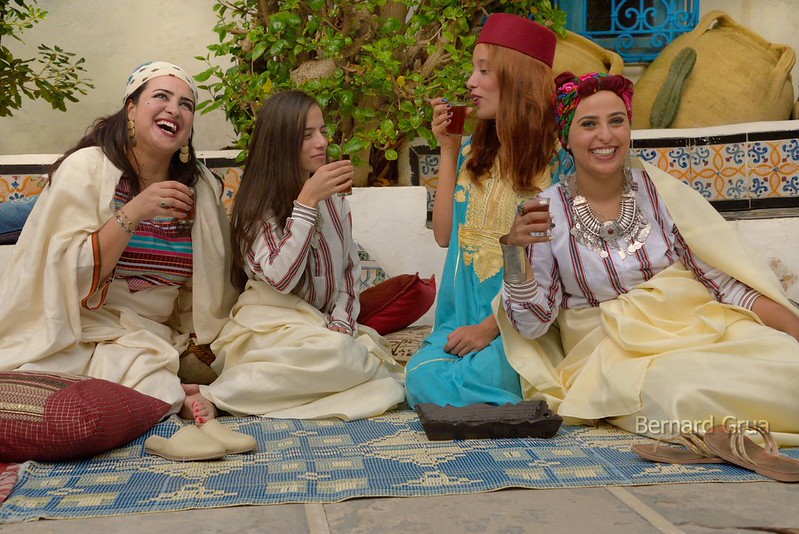 Quatre femmes et jeunes filles en costumes traditionnels boivent du thé assises dans la cour de Dar el Annabi à Sidi Bou Saïd.