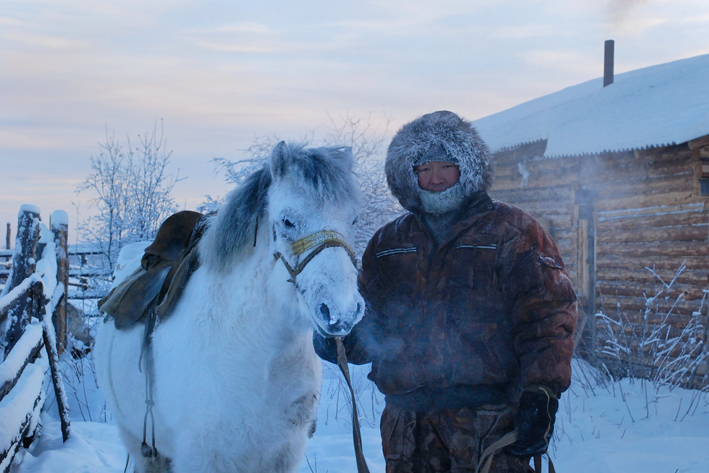 Grisha avec son cheval devant une isba à Tomtor, par −50 °C, en Iakoutie.
