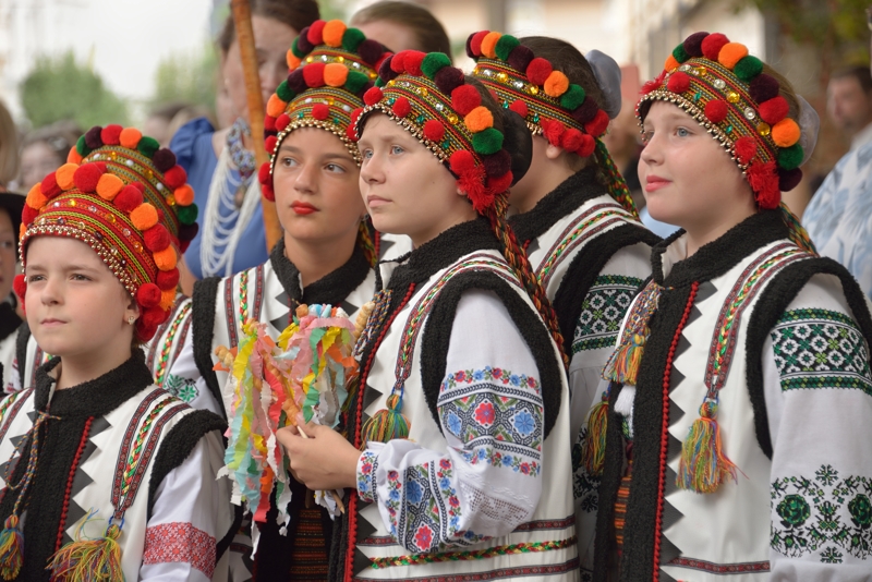 Groupe de jeunes filles houtsoules portant des coiffes traditionnelles ornées de pompons colorés.