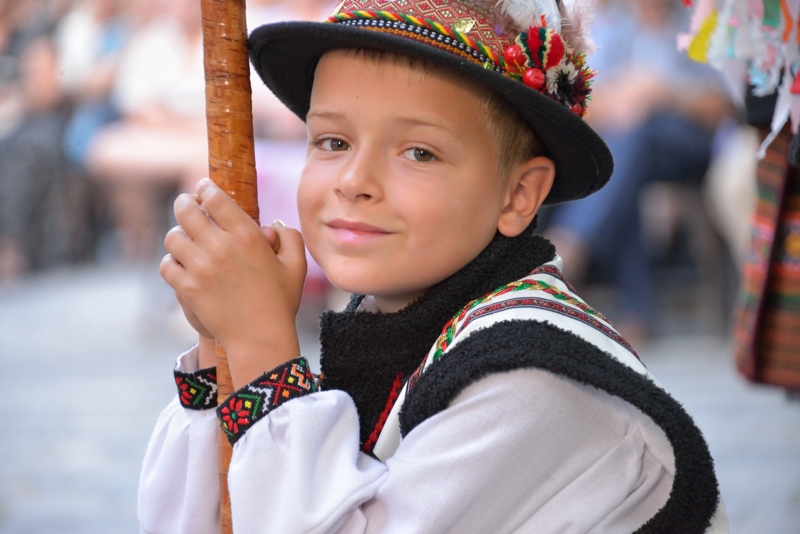 Jeune garçon houtsoule souriant, portant un chapeau traditionnel et tenant une trompe.