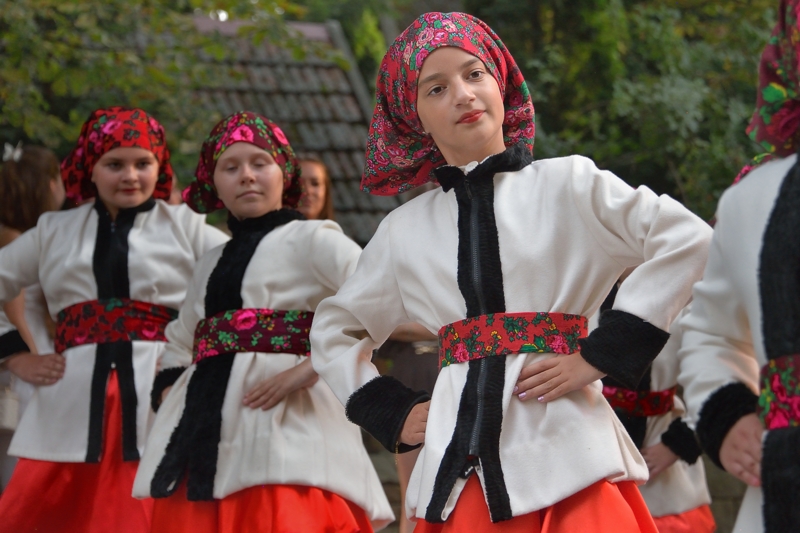 Jeunes filles houtsoules dansant en groupe, vêtues de costumes traditionnels blancs et rouges.