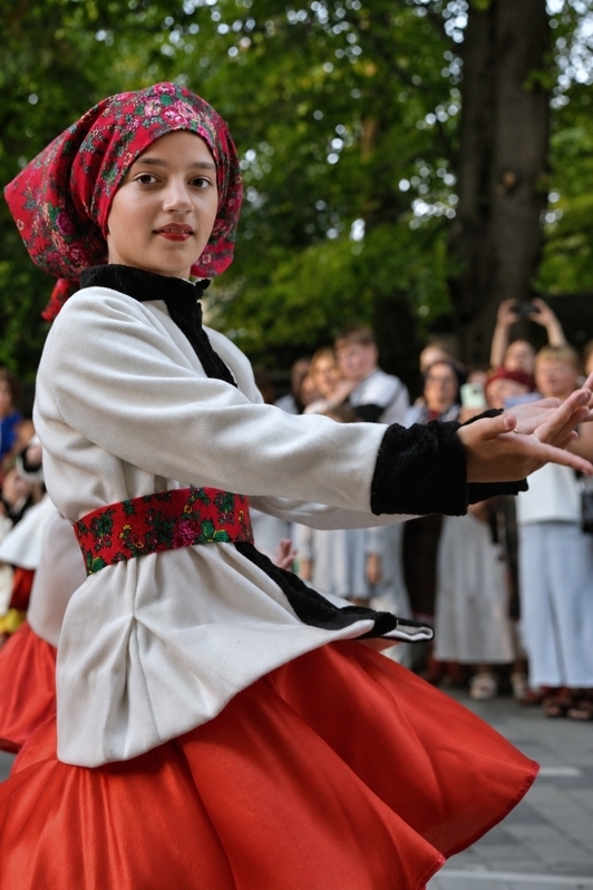 Jeune danseuse houtsoule en costume traditionnel, les bras tendus pendant une danse à Kolomyia.