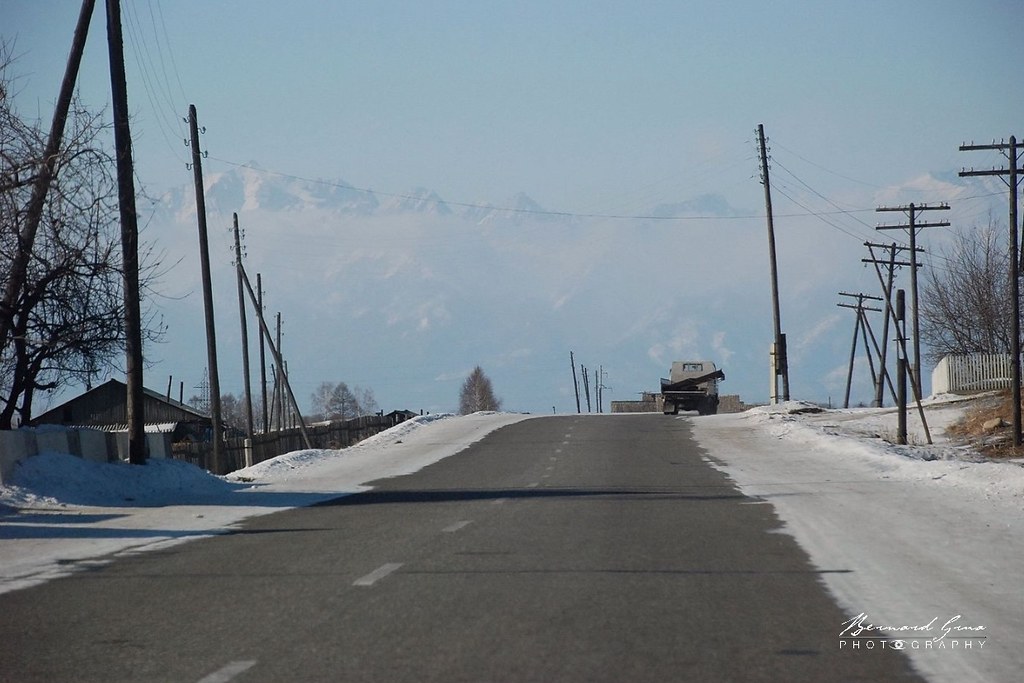 Route en hiver à l'entrée de la vallée de la Tounka. En arrière plan, la chaîne des Saïans orientaux © Bernard Grua