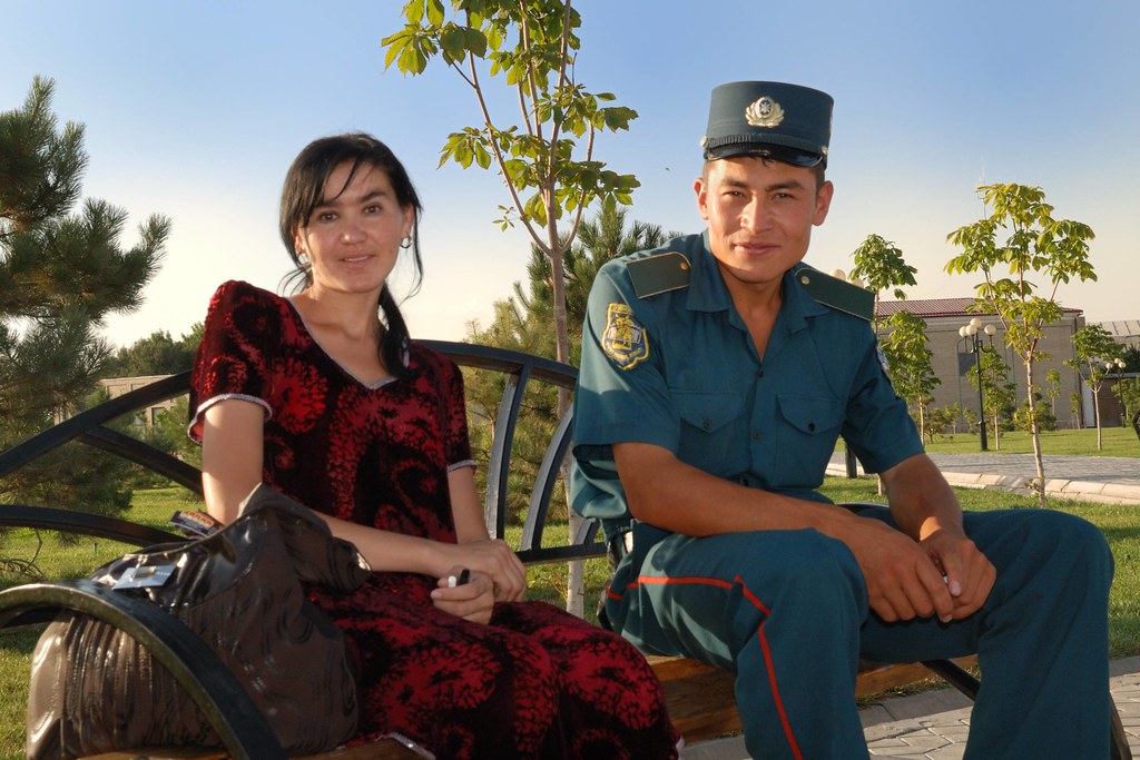 Jeune femme ouzbèke assise à côté d’un homme en uniforme militaire, dans un parc de Samarcande.